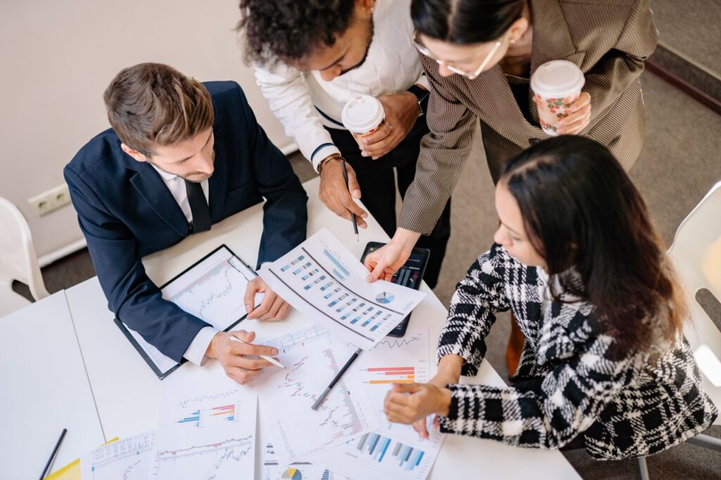A diverse team in business attire collaborates over graphs and charts for a successful project.